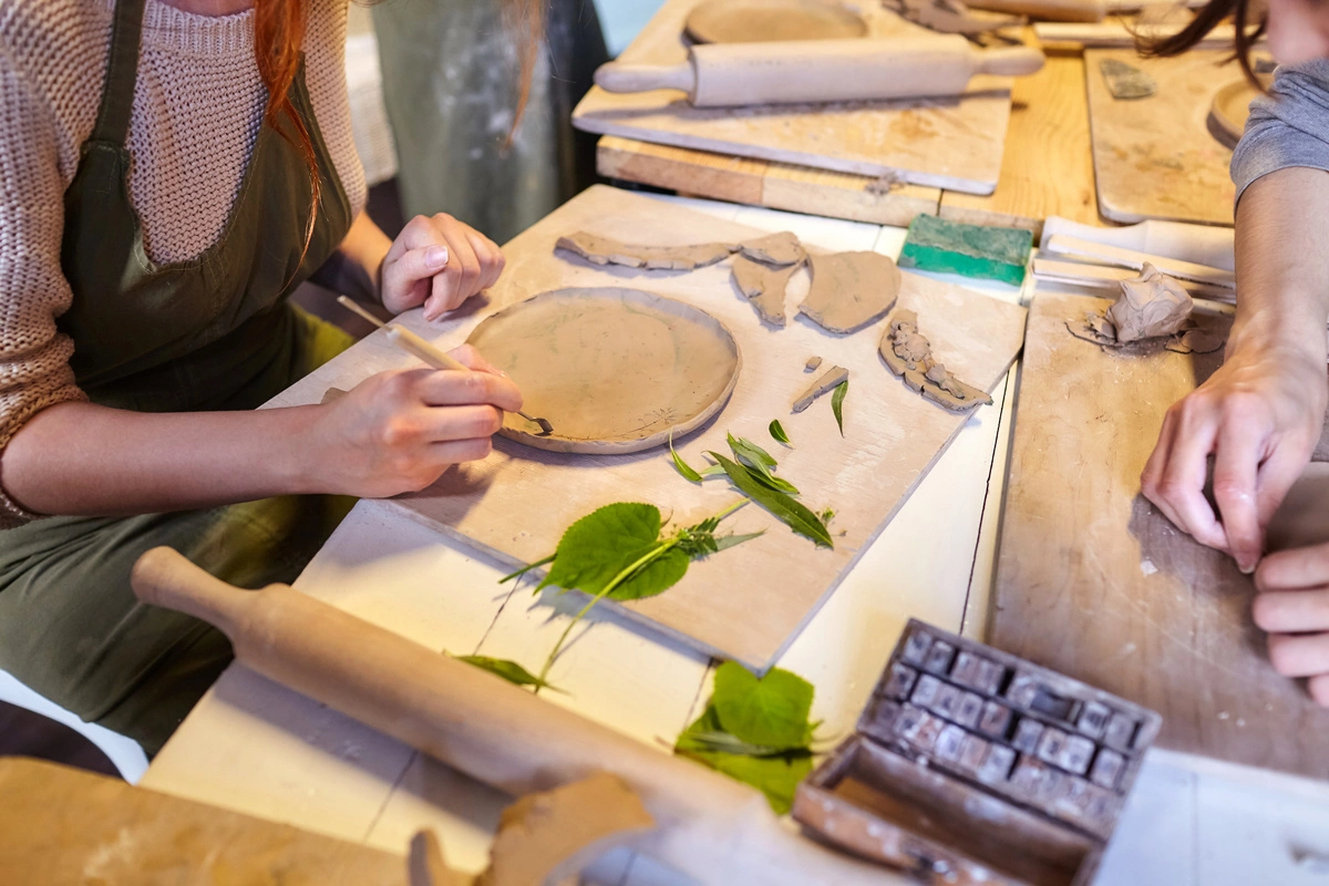 Personnes travaillant avec de l'argile et des feuilles lors d'un atelier d'art-thérapie, illustrant l'utilisation de la créativité pour le bien-être émotionnel.