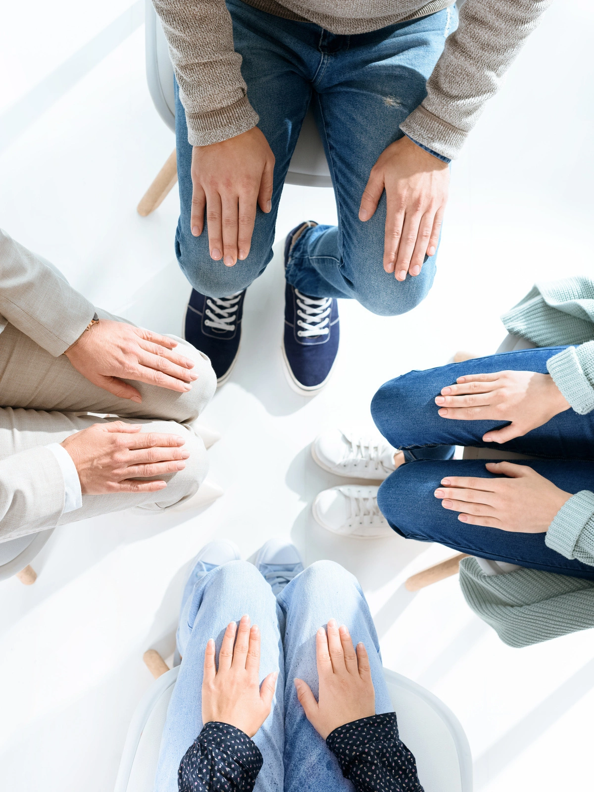 Groupe de personnes assises en cercle, les mains sur les genoux, participant à un atelier thérapeutique, favorisant l'échange et le soutien mutuel.