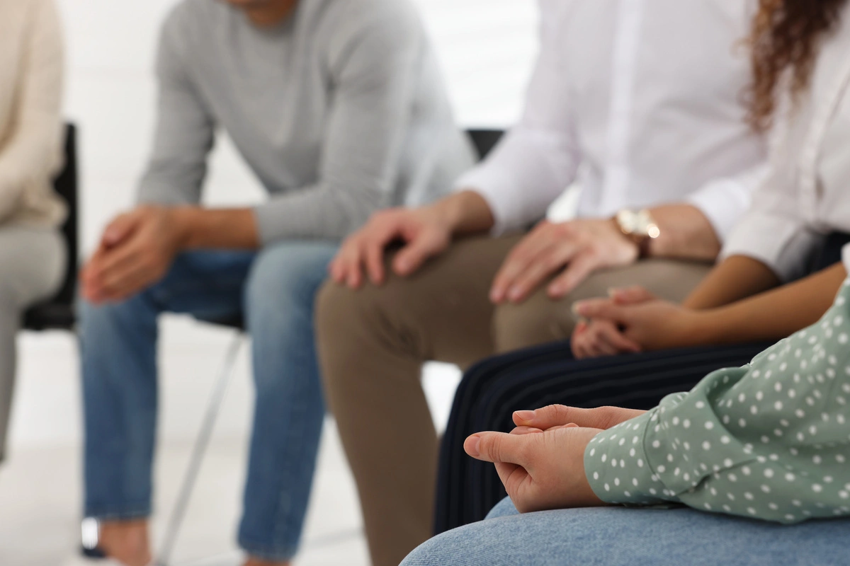 Groupe de personnes assises en cercle lors d'une séance de thérapie de groupe, se soutenant mutuellement dans un environnement thérapeutique.